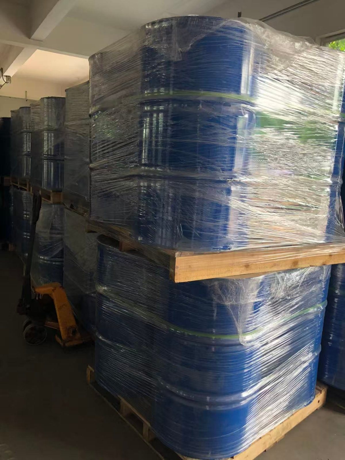 托盘上缠膜打包的 200 升蓝色铁桶